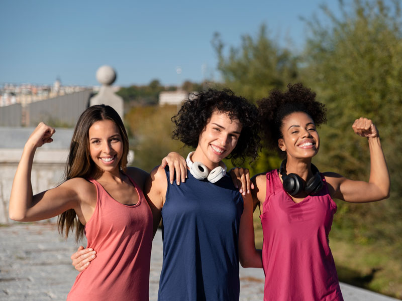 Imagem com um grupo de pessoas sorridentes usando as blusas fitness em um ambiente de treino.